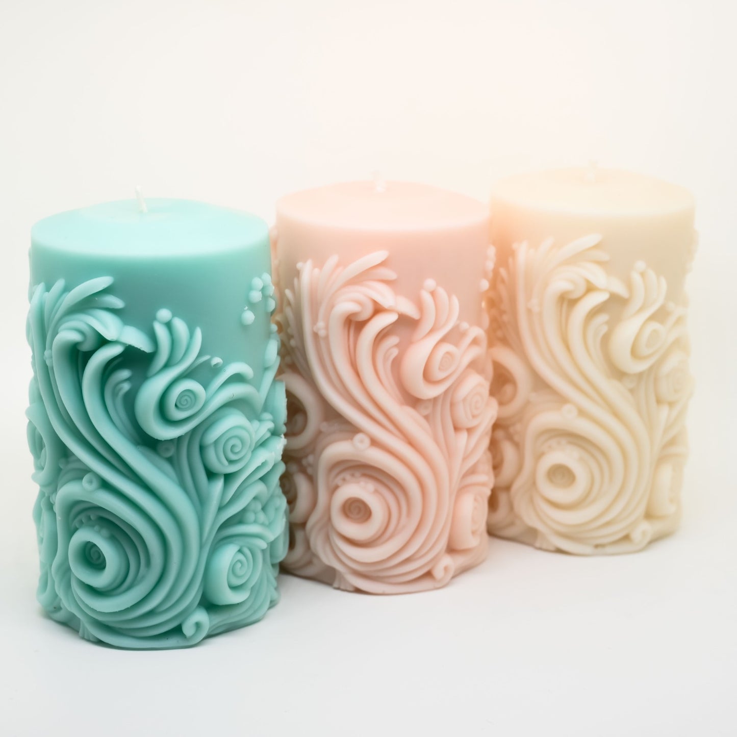 שלושה נרות ריחניים מעוצבים
ומעוטרים בסלסולים בשורה אלכסונית - הימיני בצבע לבן, האמצעי בצבע חלמון והשמאלי בצבע ירקרק עדין