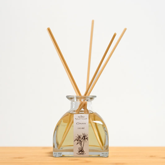 מפיץ ריח 150 מ"ל בניחוח אואזיס עם מקלות דמויי עץ, בכלי זכוכית יפהפה בצורת פירמידה עם פאות מקומרות אטום בפקק שעם – ועליו איור שחור של דקלים בנווה מדבר.