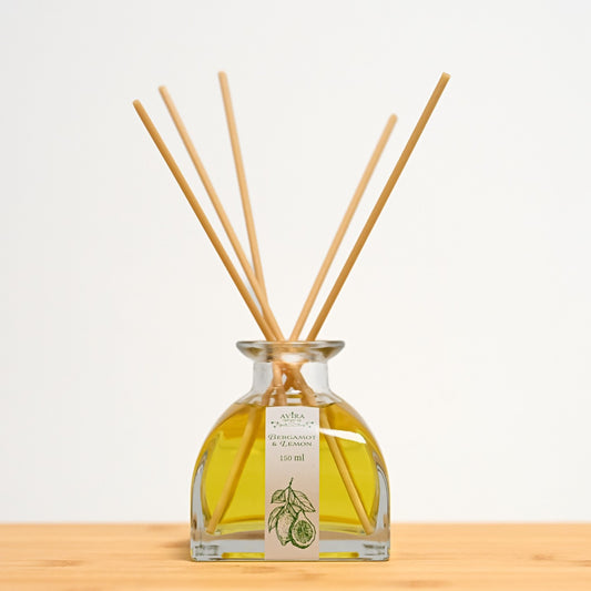 מפיץ ריח 150 מ"ל בניחוח ברגמוט ולימון עם מקלות דמויי עץ, בכלי זכוכית יפהפה בצורת פירמידה עם פאות מקומרות אטום בפקק שעם – ועליו איור ירקרק של הדרים.