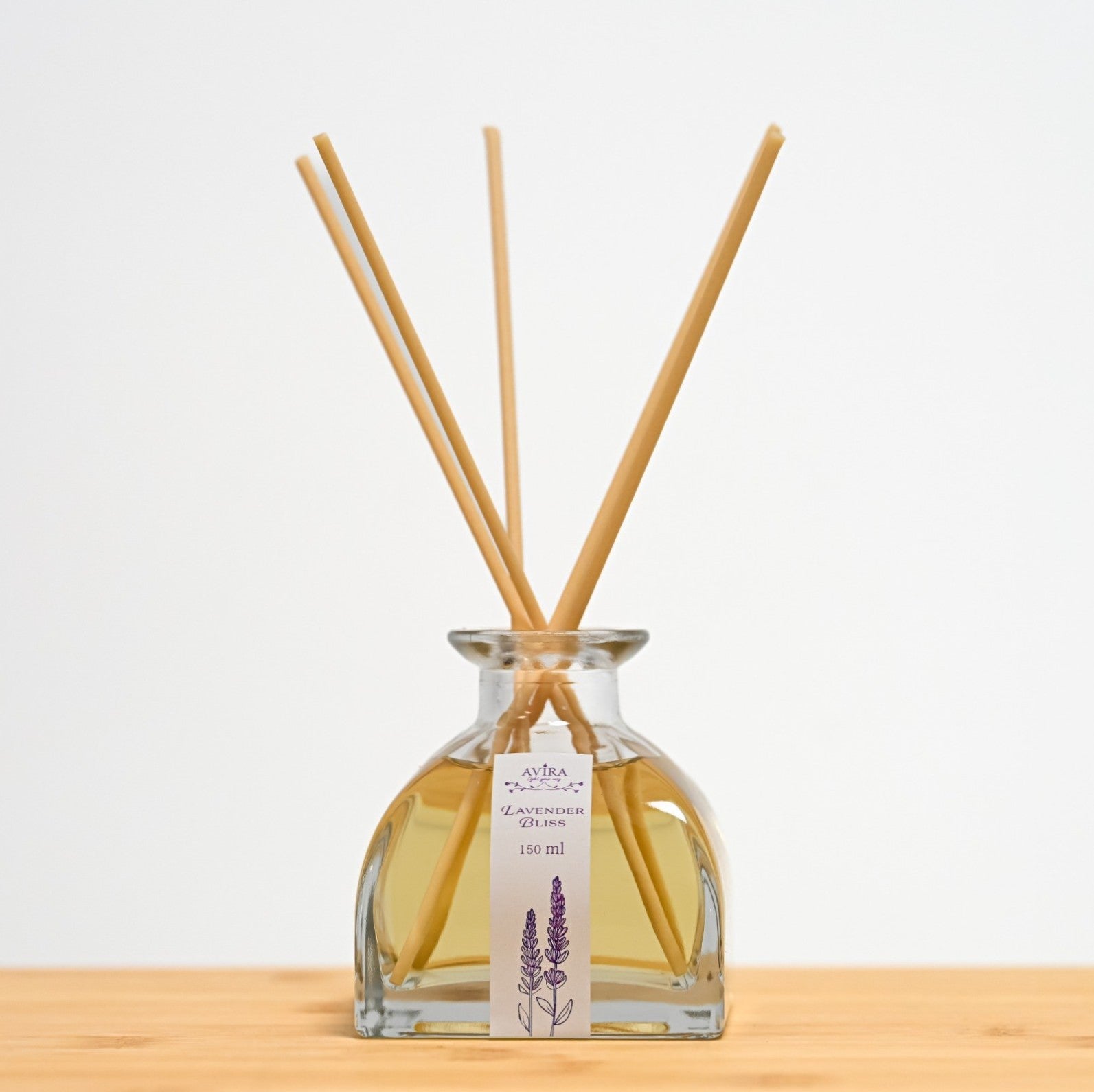 מפיץ ריח 150 מ"ל בניחוח לבנדר מפנק עם מקלות דמויי עץ, בכלי זכוכית יפהפה בצורת פירמידה עם פאות מקומרות אטום בפקק שעם – ועליו איור סגלגל של צמחי לבנדר.