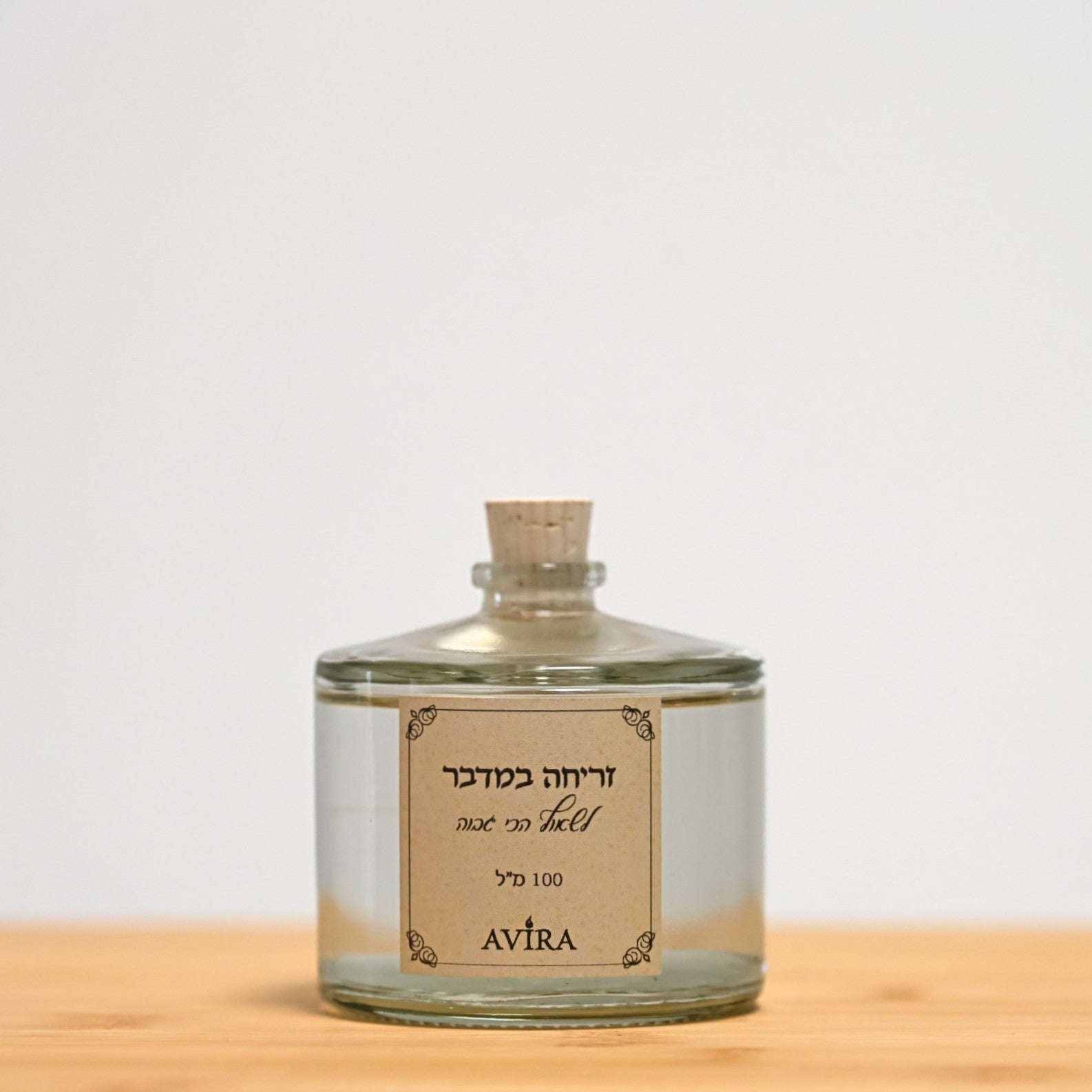 מפיץ ריח 100 מ"ל בניחוח זריחה במדבר, בכלי זכוכית עגלגל שקוף, אטום בפקק שעם – ועליו הכיתוב "לשאוף הכי גבוה".