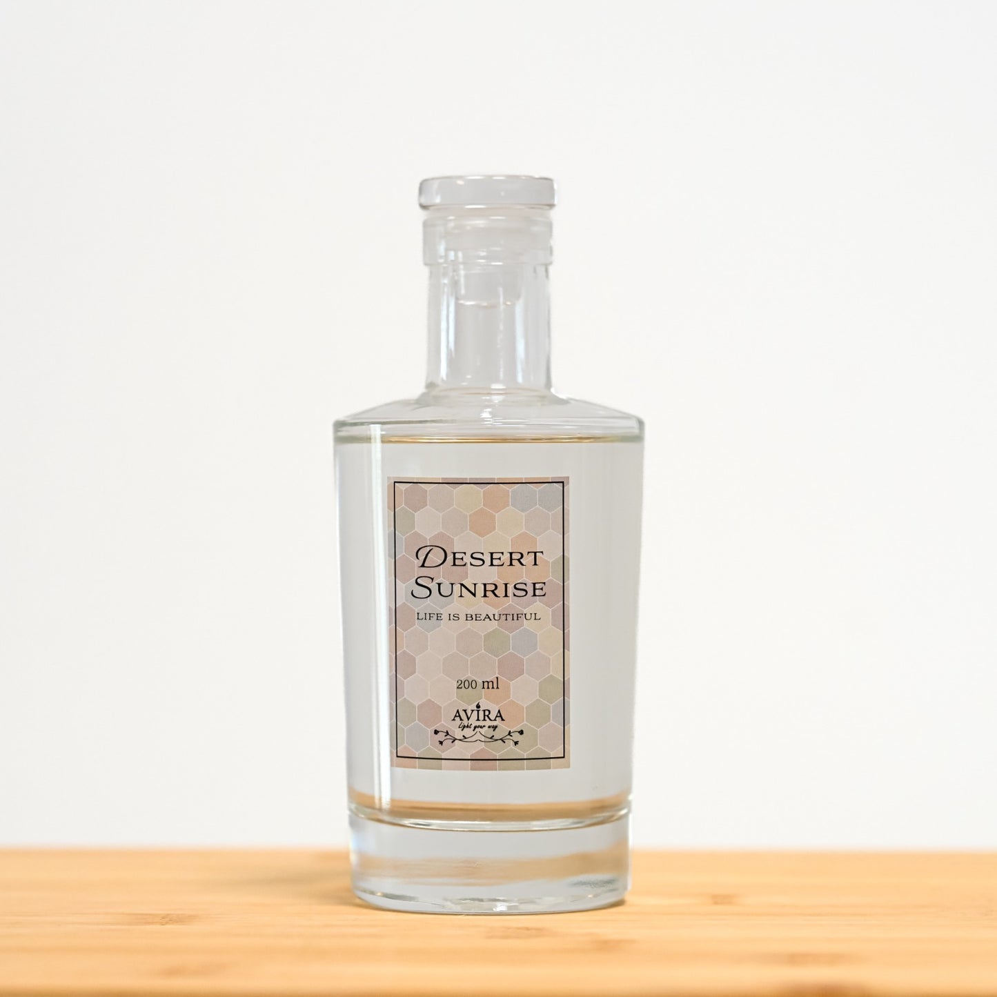 מפיץ ריח 200 מ"ל בניחוח זריחה במדבר בכלי זכוכית שקוף, אטום בפקק וינילוק – ועליו הכיתוב "LIFE IS BEAUTIFUL".