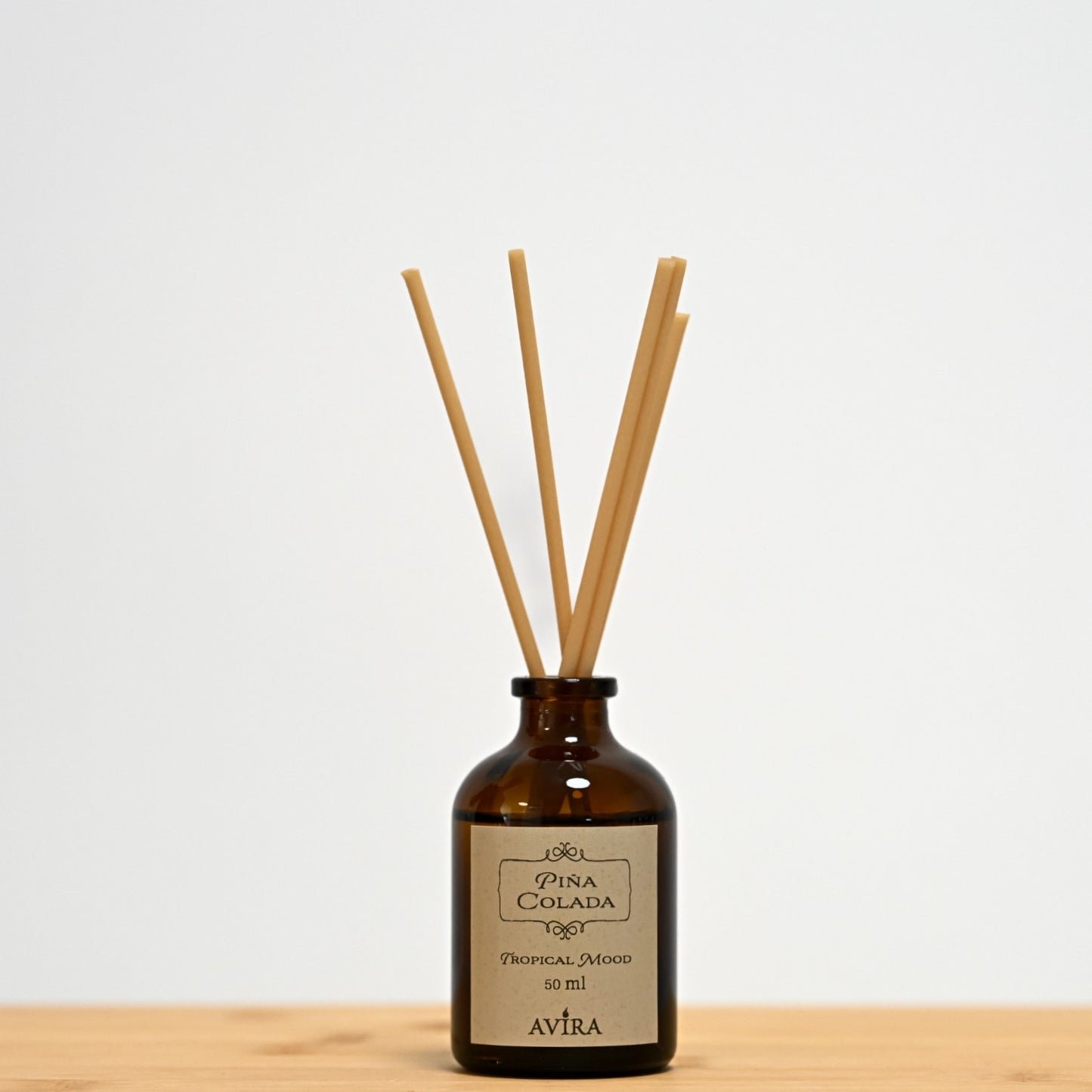 מפיץ ריח 50 מ"ל בניחוח פינה קולדה עם מקלות דמויי עץ, בכלי זכוכית חום ("בקבוק רוקחים") אטום בפקק שעם – ועליו מדבקה עם הכיתוב "TROPICAL MOOD".
