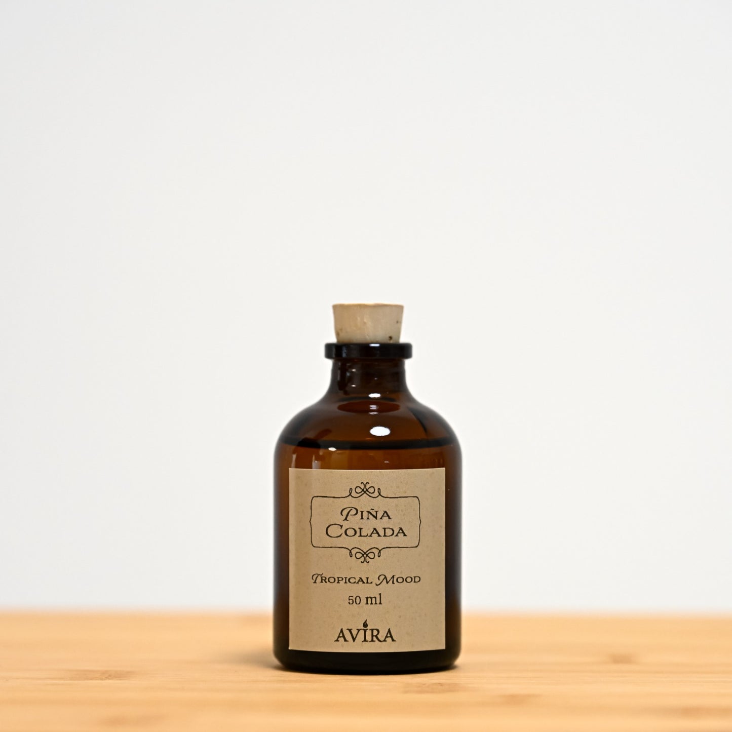 מפיץ ריח 50 מ"ל בניחוח פינה קולדה, בכלי זכוכית חום ("בקבוק רוקחים") אטום בפקק שעם – ועליו מדבקה עם הכיתוב "TROPICAL MOOD".