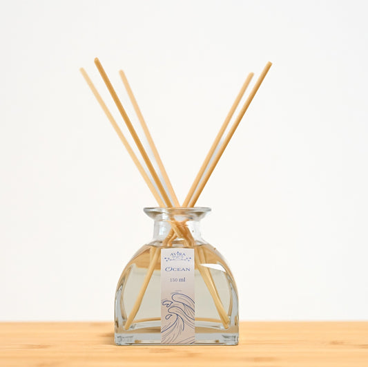 מפיץ ריח 150 מ"ל בניחוח אושן עם מקלות דמויי עץ, בכלי זכוכית יפהפה בצורת פירמידה עם פאות מקומרות אטום בפקק שעם – ועליו איור כחול של גלי אוקיינוס.