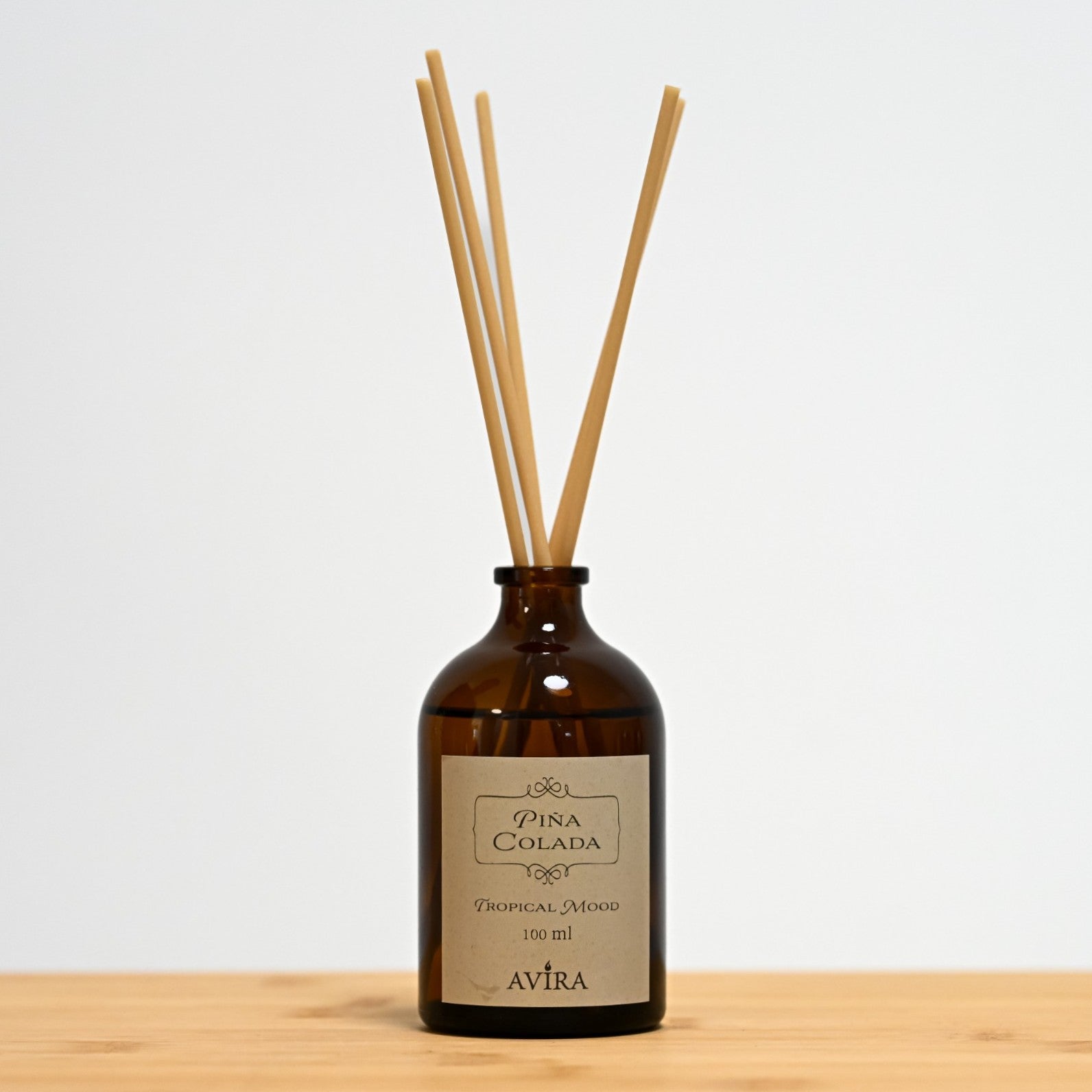 מפיץ ריח 100 מ"ל בניחוח פינה קולדה עם מקלות דמויי עץ, בכלי זכוכית חום ("בקבוק רוקחים") אטום בפקק שעם – ועליו מדבקה עם הכיתוב "TROPICAL MOOD".