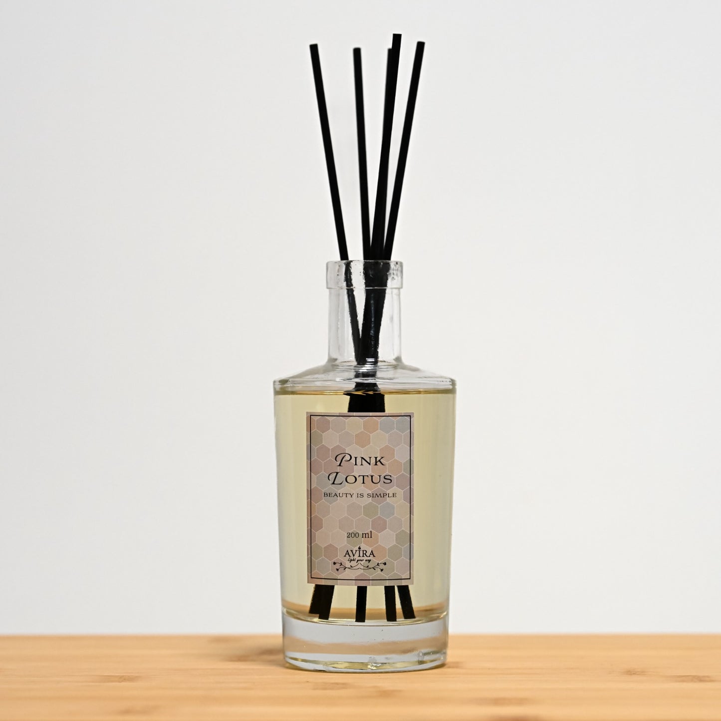 מפיץ ריח 200 מ"ל בניחוח לוטוס ורוד עם מקלות שחורים בכלי זכוכית שקוף, אטום בפקק וינילוק – ועליו הכיתוב "BEAUTY IS SIMPLE".