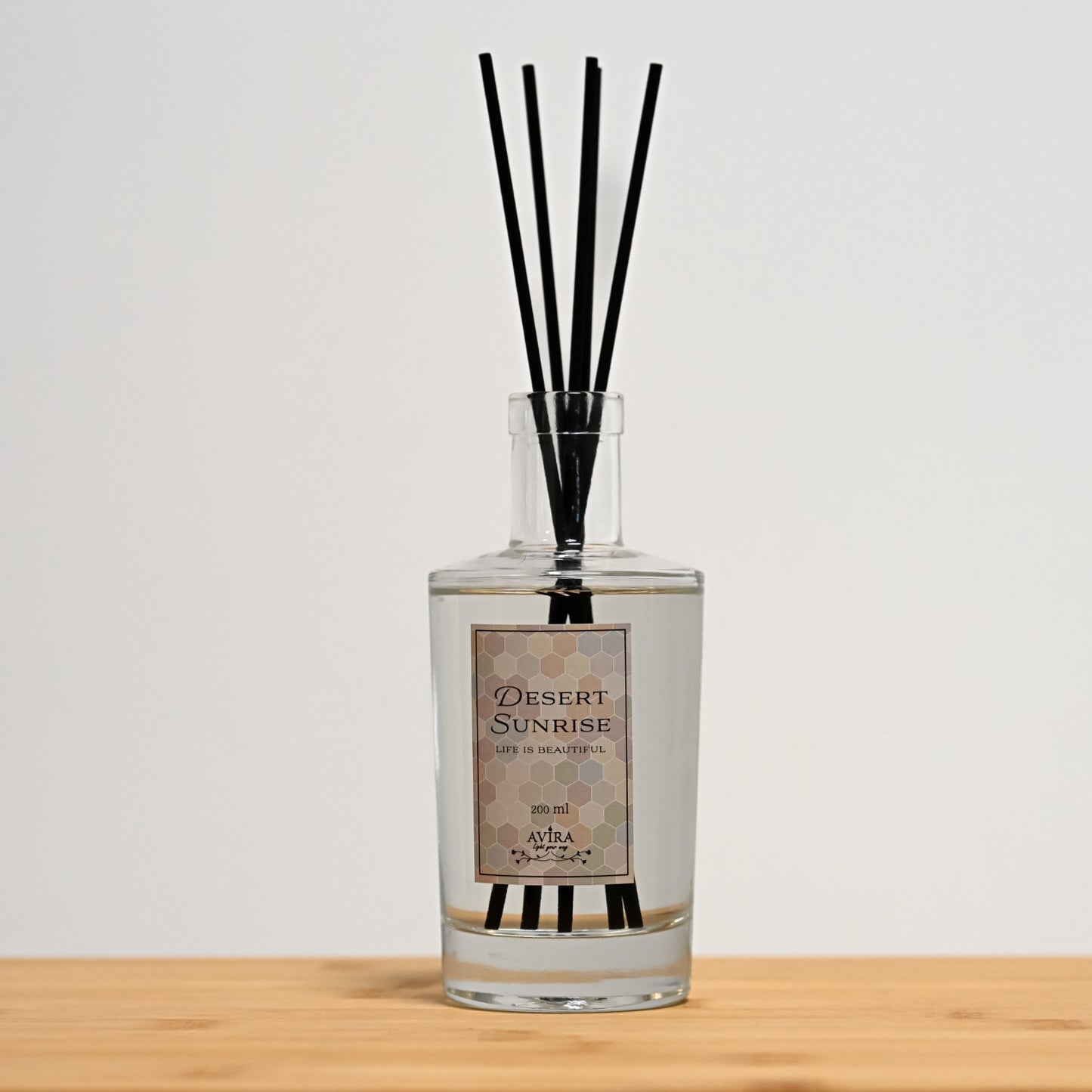 מפיץ ריח 200 מ"ל בניחוח זריחה במדבר עם מקלות שחורים בכלי זכוכית שקוף, אטום בפקק וינילוק – ועליו הכיתוב "LIFE IS BEAUTIFUL".