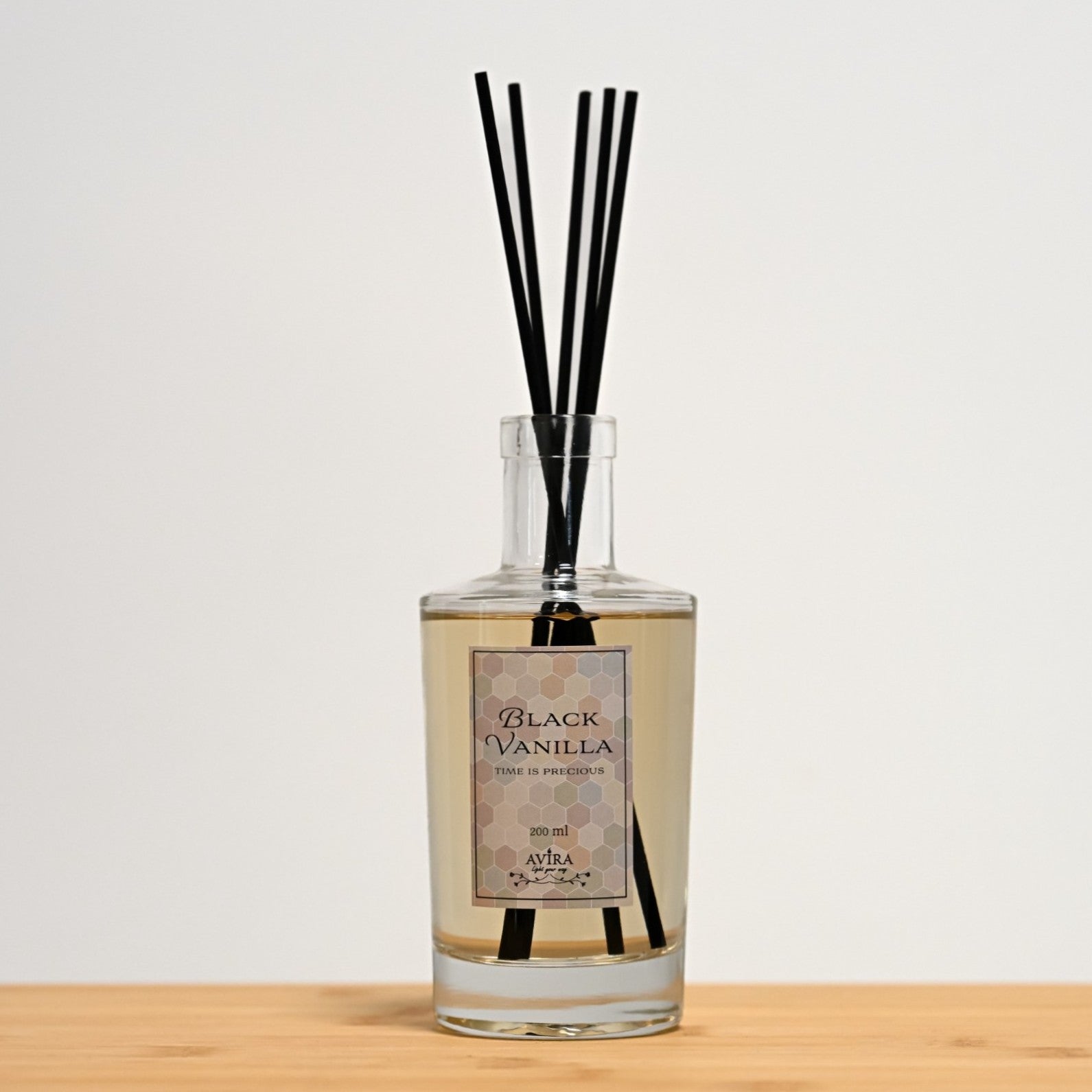 מפיץ ריח 200 מ"ל בניחוח בלאק ונילה עם מקלות שחורים בכלי זכוכית שקוף, אטום בפקק וינילוק – ועליו הכיתוב "TIME IS PRECIOUS".