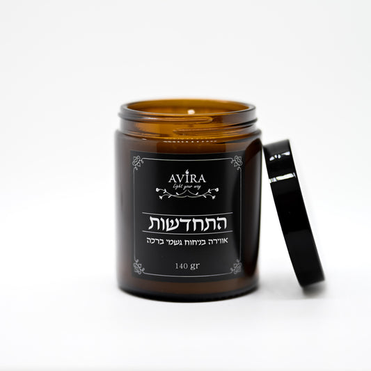 נר 140 גרם בניחוח גשמי ברכה בתוך צנצנת חומה יוקרתית - ועל הצנצנת מדבקה שחורה עם הכיתוב "התחדשות"